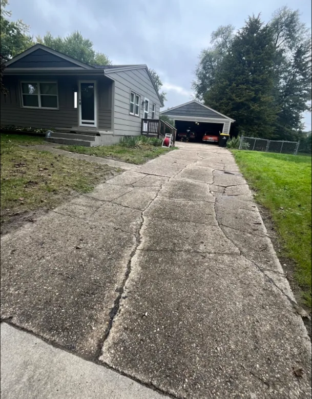 Cracked and heaving concrete driveway at a Des Moines house before Medina Concrete replaced it