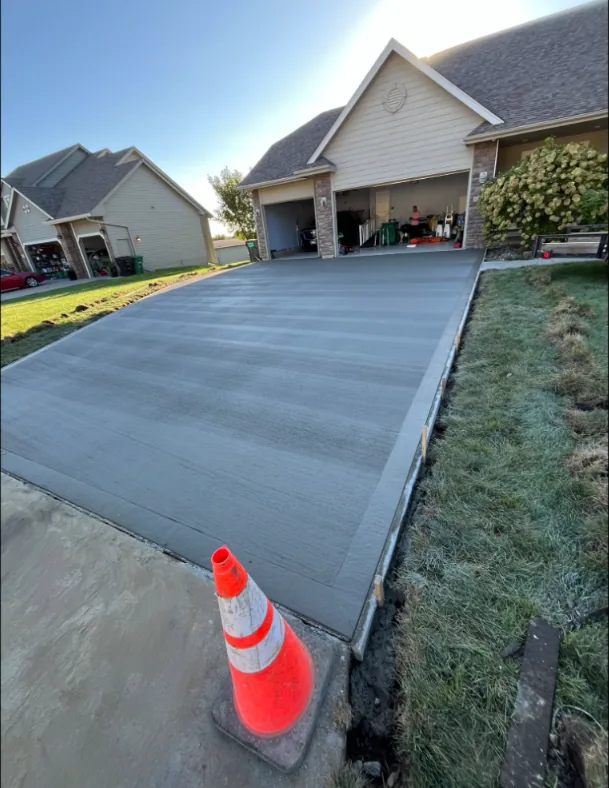 New broom-finished concrete driveway in front of a two-car garage, poured by Medina Concrete in Des Moines